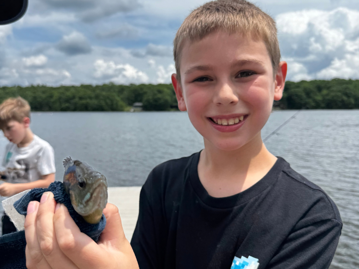 Oliver holding a fish while on the lake