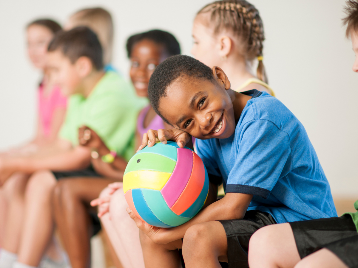 Stock photo of young boy smiling with a ball in his lap